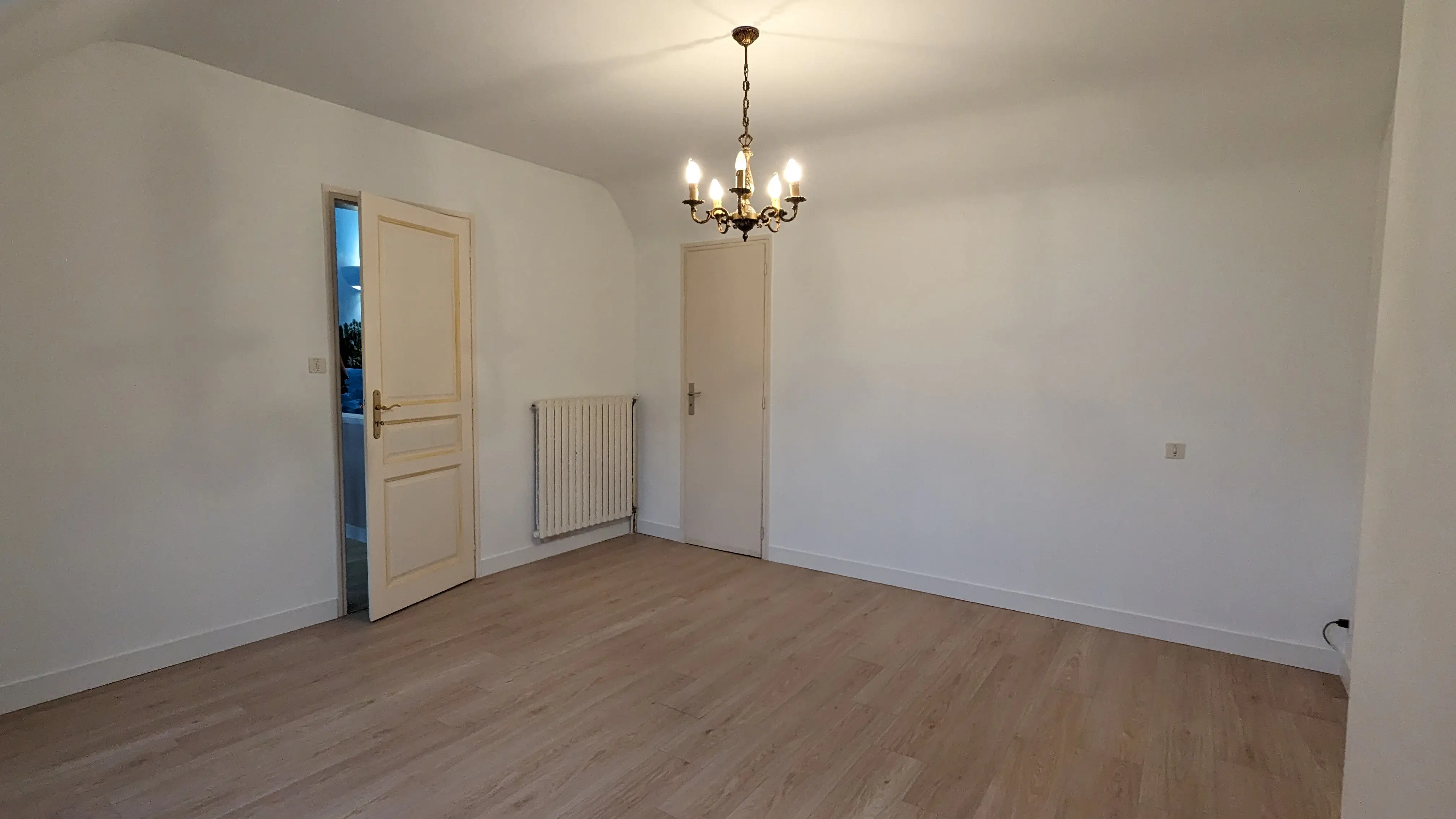 Chambre rénové aux murs et plafonds blancs avec un sol en parquet flottant composé de lame à clipser.