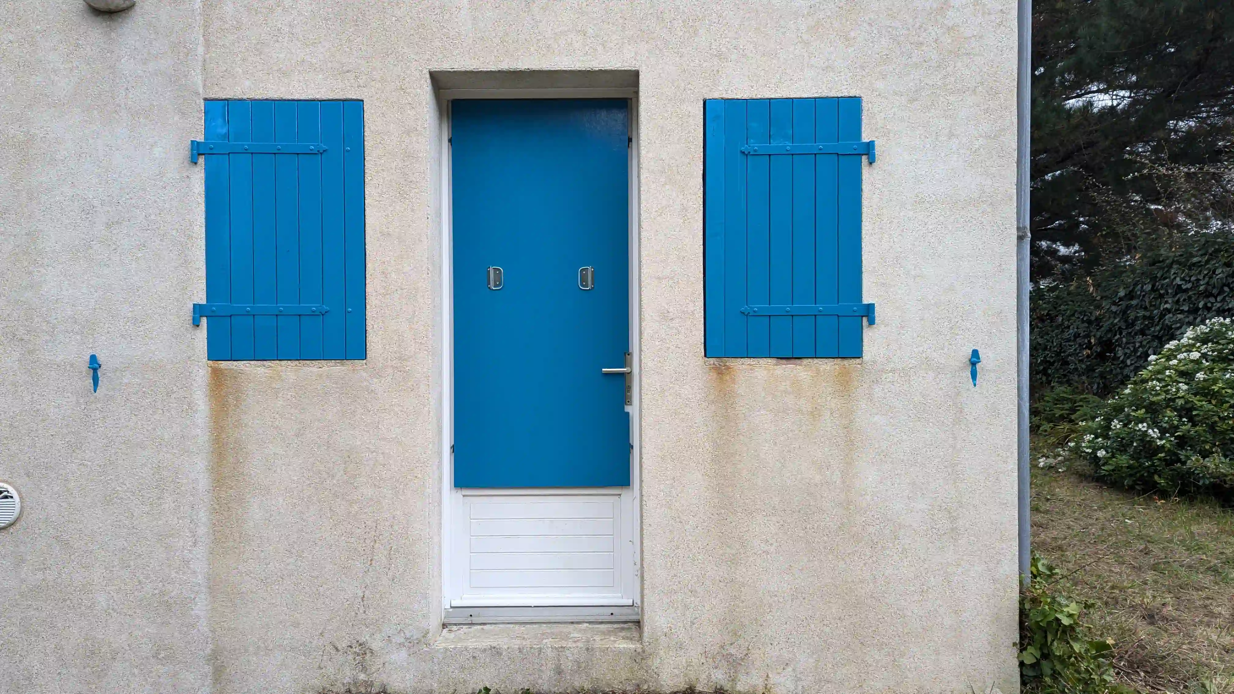 Ensemble de portes et volet peint en blanc et bleu.